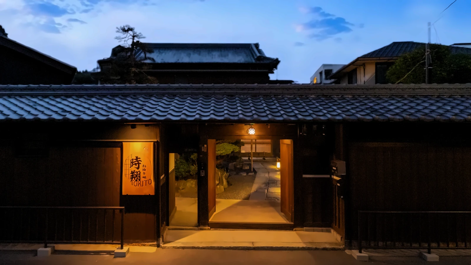 薄暮の宿本陣 時翔。藍色の空の下、瓦屋根の門口に「時翔」の看板灯がともる